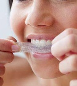 woman using a tooth whitening strip